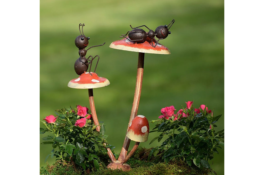 Metal garden accent of two ants relax on a trio of mushrooms.