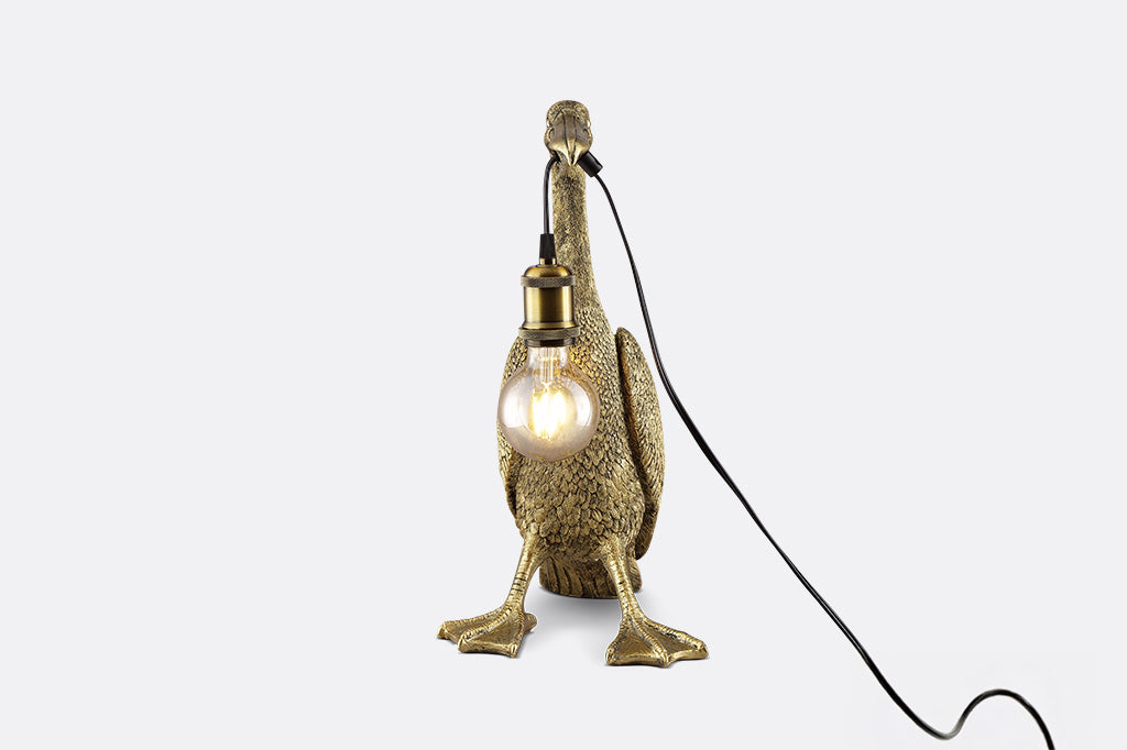 front view of novelty desk lamp of pelican holding lightbulb by the beak - gold finished resin