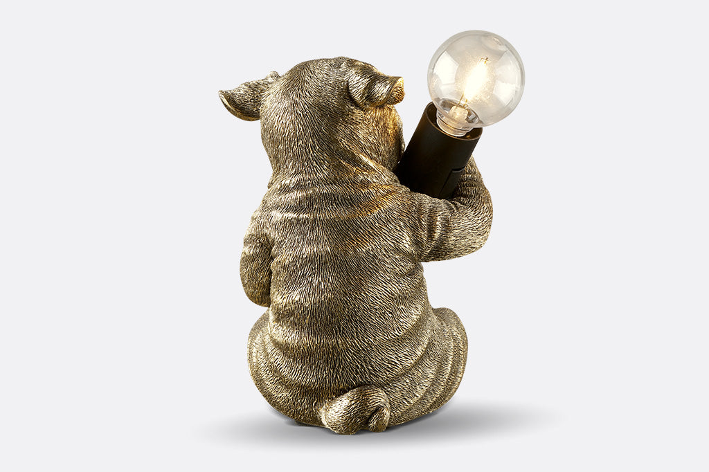 back view of gold finished resin novelty desk lamp of french bulldog holding lightbulb.