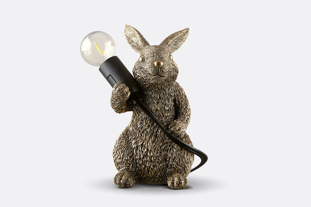 novelty desk lamp of gold finished resin. A rabbit holding lightbulb over its shoulder