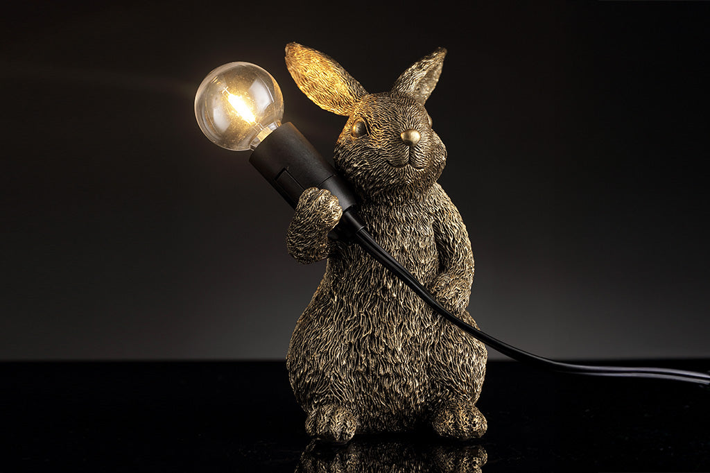 novelty desk lamp of gold finished resin. A rabbit holding lightbulb over its shoulder