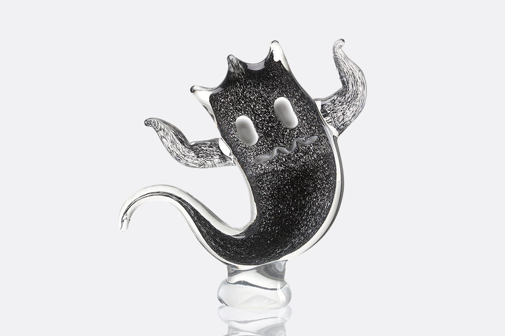 Black speckled glass sculpture of a ghost on a white background