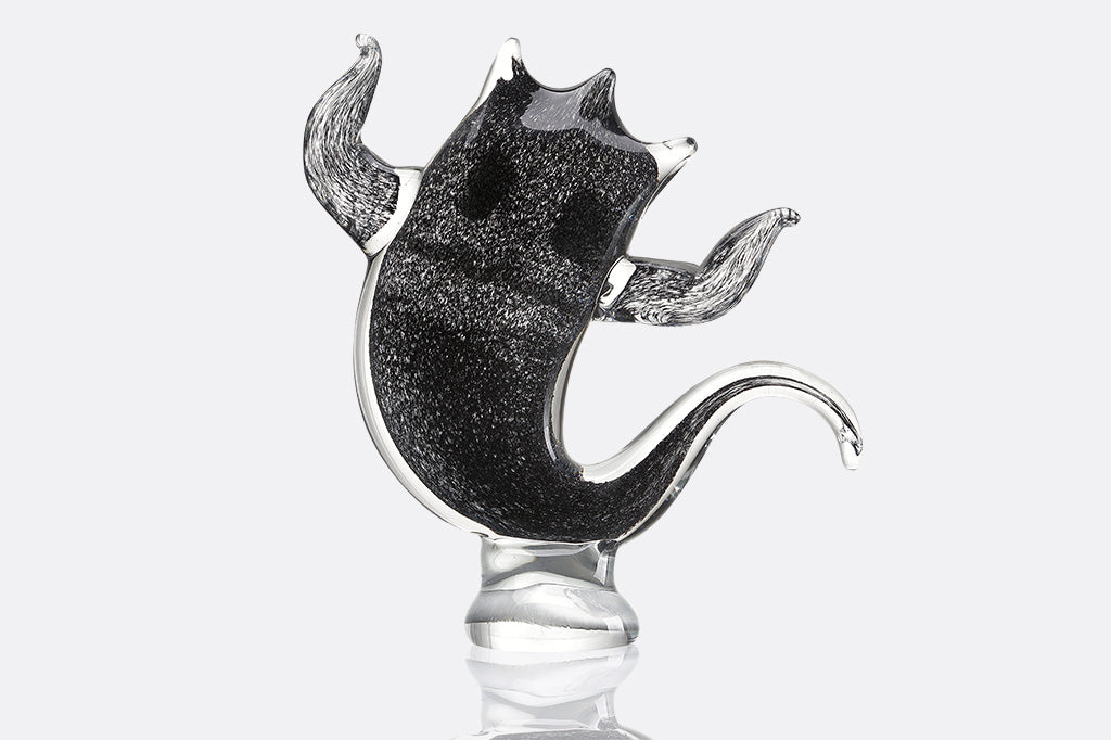 Black speckled glass sculpture of a ghost on a white background