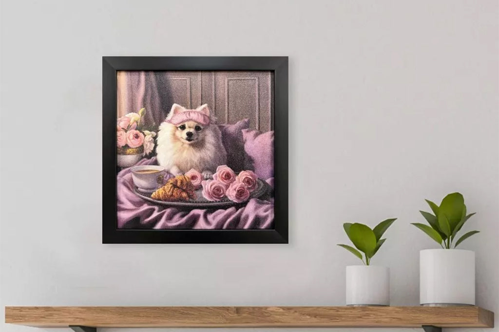 Framed artwork of a dog wearing a pink sleeping mask with a coffee cup, croissant, and flowers on a bed.