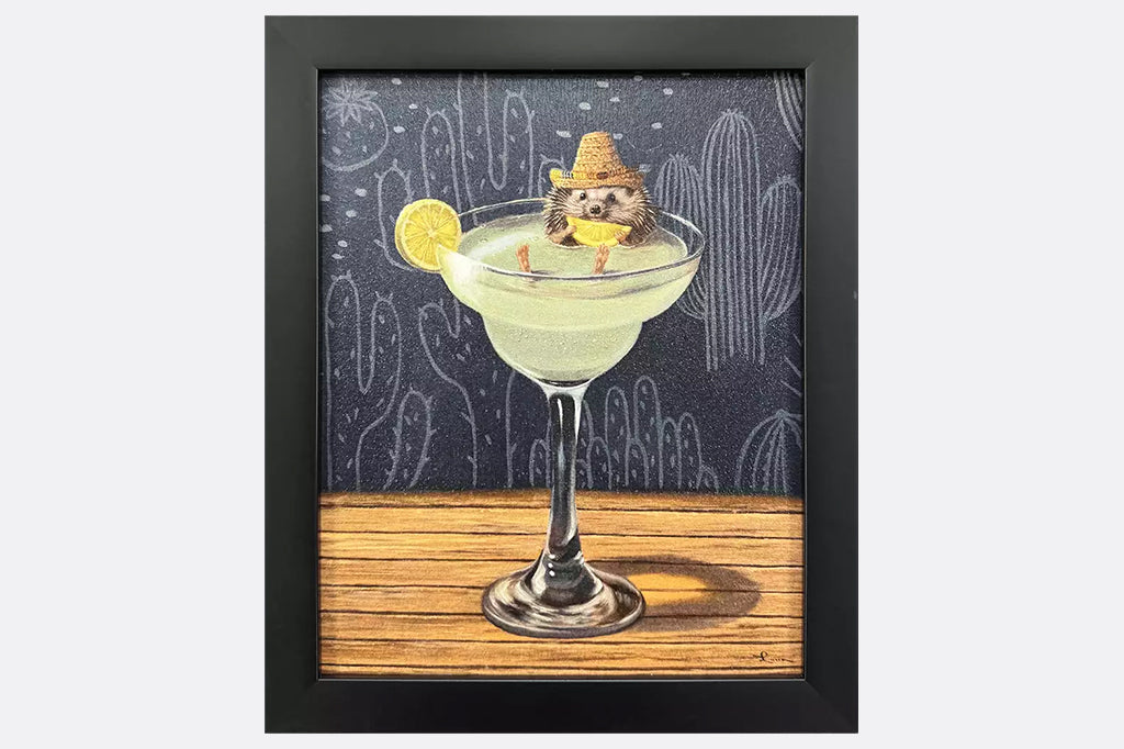 Framed artwork of a hedgehog wearing a sombrero sitting inside of a margarita glass with a cactus background.