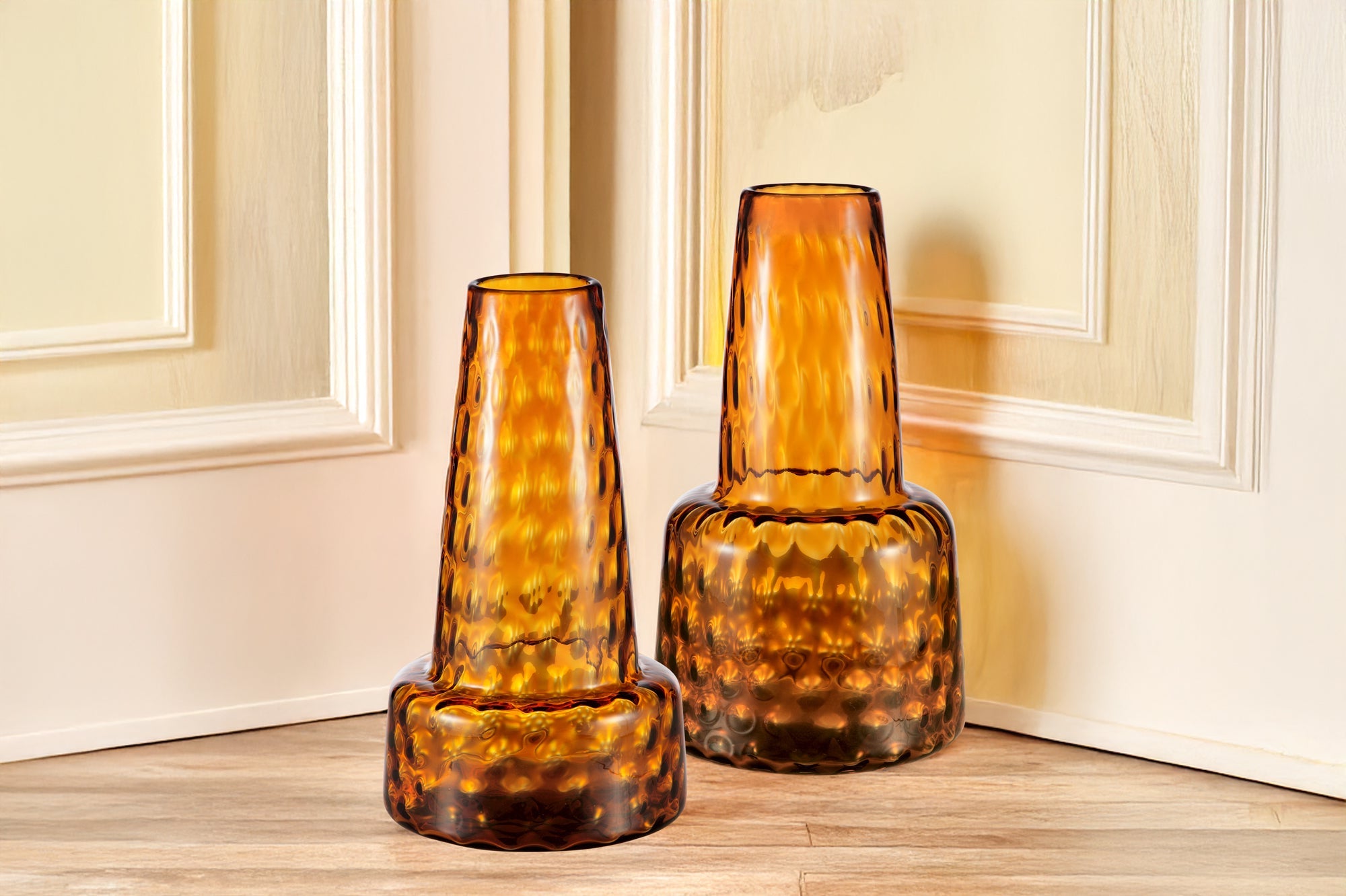 large ochre display glass vases shown on wood floor by wood paneled doors in home setting