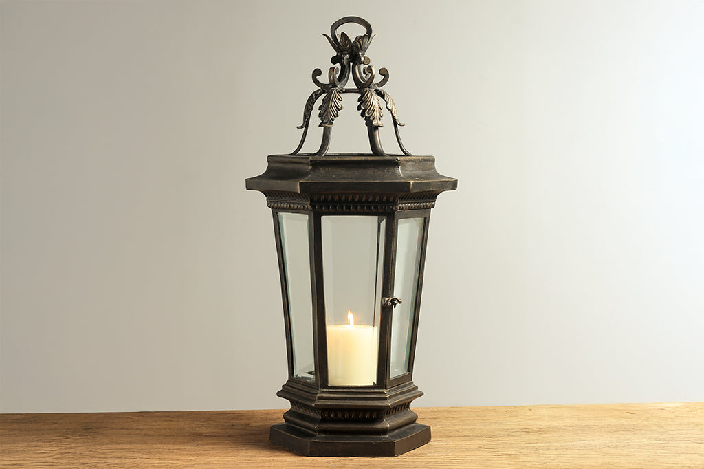 Decorative lantern with a candle on a wooden surface and light gray background