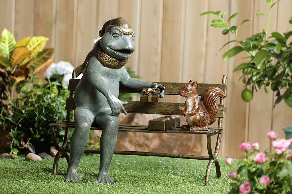 Frog and squirrel statue gifting an acorn on a bench in a garden setting