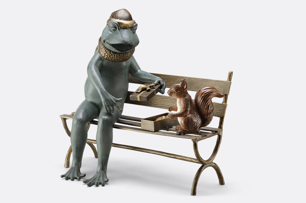 Frog and squirrel statue gifting an acorn on a bench