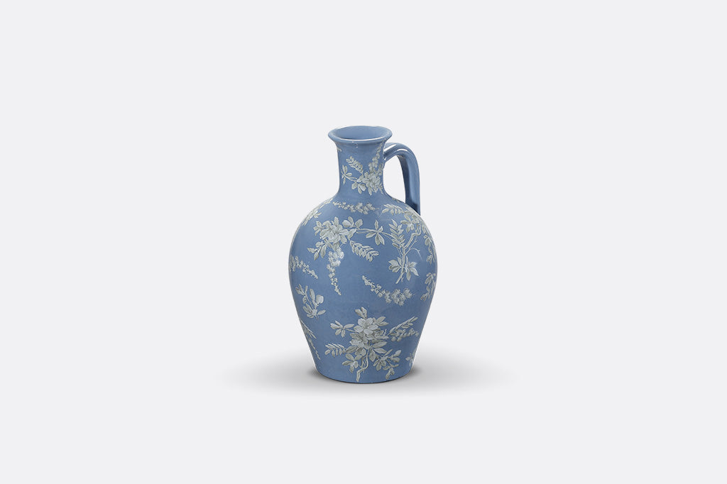A short blue ceramic vase with white cornflower designs.