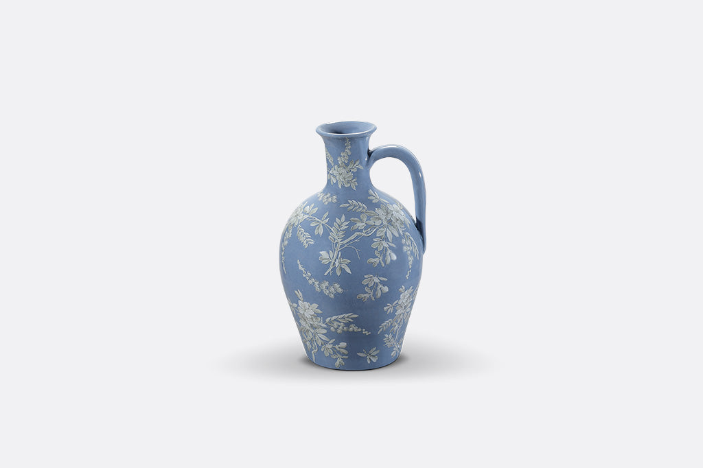 A short blue ceramic vase with white cornflower designs.
