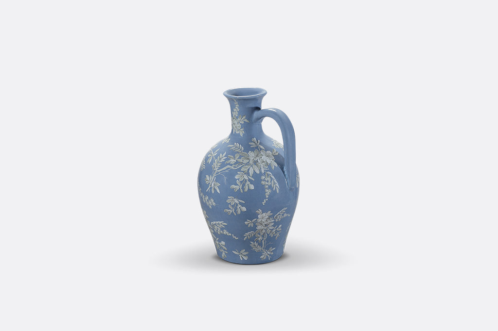 A short blue ceramic vase with white cornflower designs.