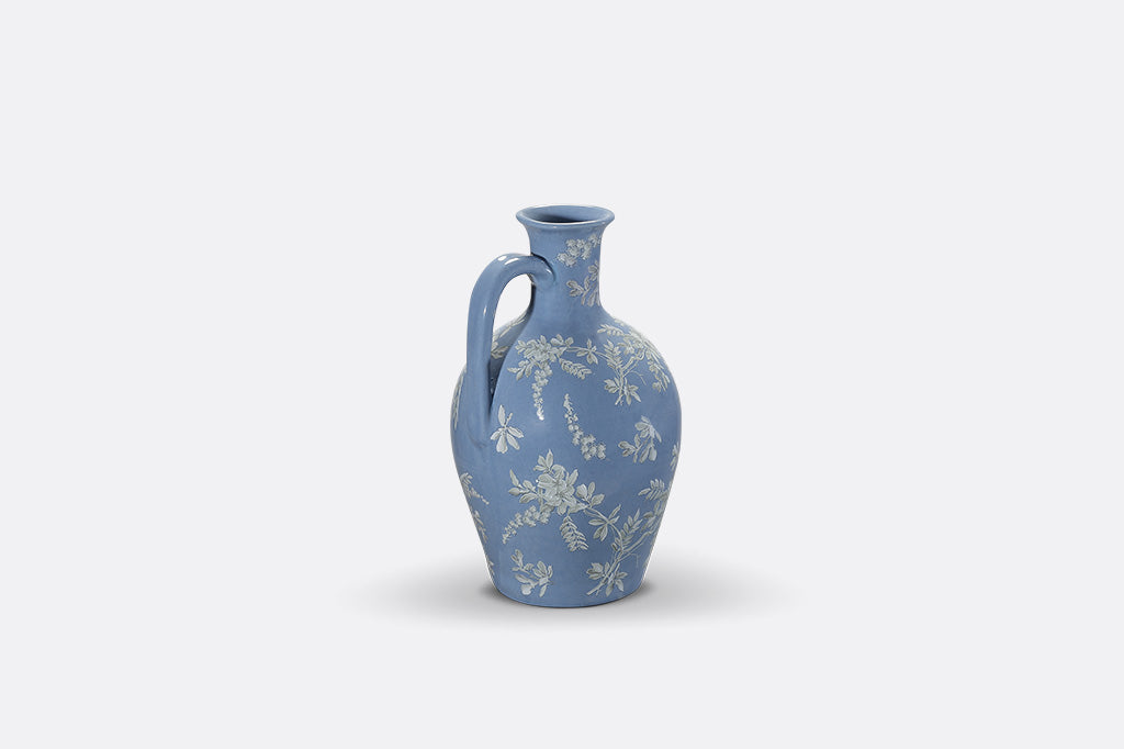 A short blue ceramic vase with white cornflower designs.
