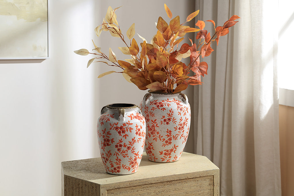 A vase jar with orange leaves and flowers.