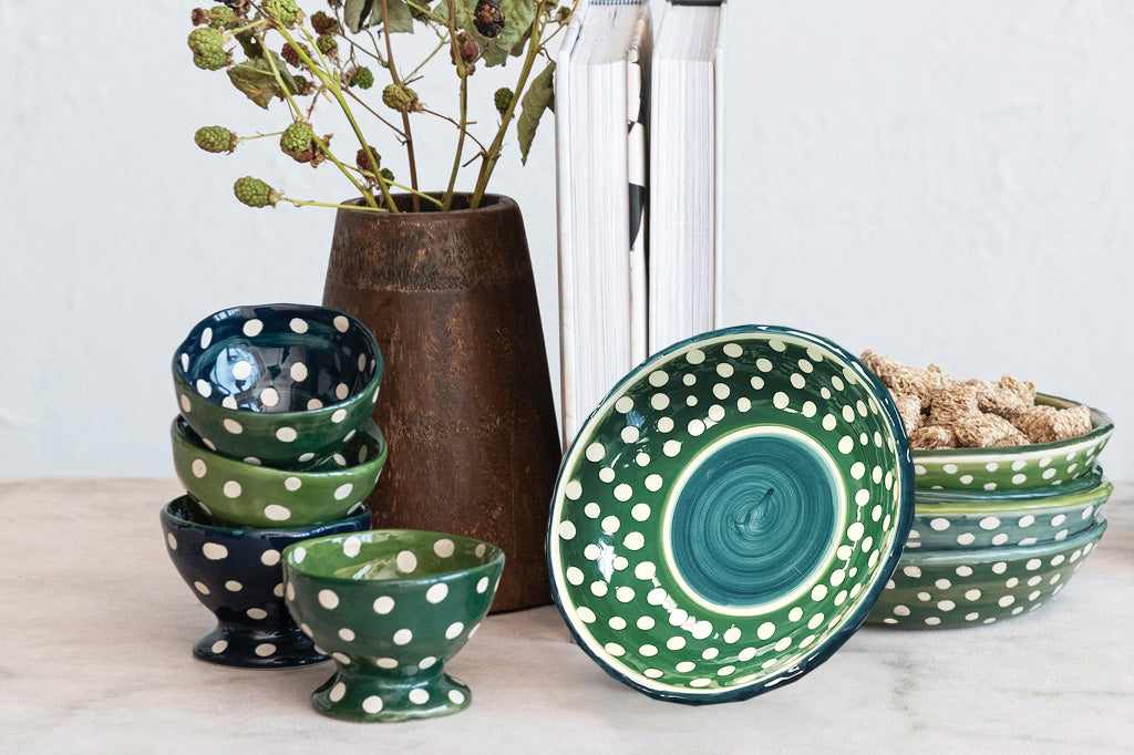 Set of four dark green with white polka dot soup bowls  shown with matching dotted footed bowls on a table