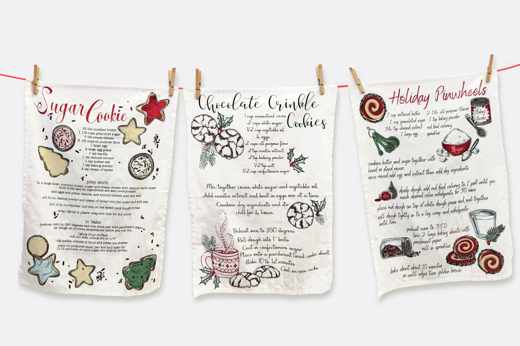 Three tea towels featuring cookie recipes shown clothepinned to a line