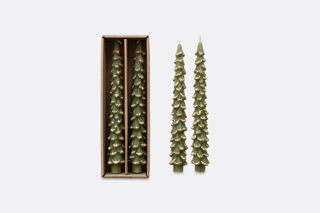 four green christmas tree shaped taper candles with gold highlights. Two pictured in packaging and two next to those, on light grey background