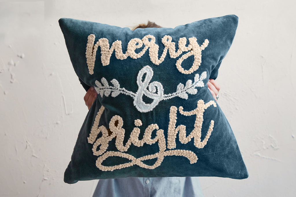 blue velvet pillow with script phrase reading merry & bright 