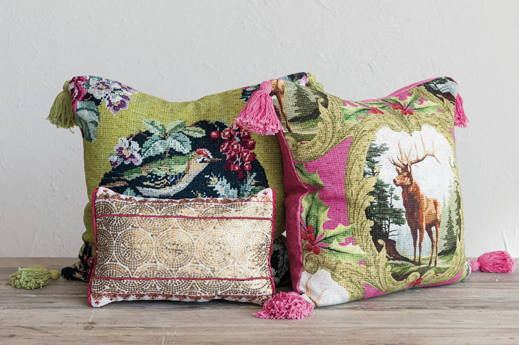 Floral and bird embroidered pillow with tassels with two other pillows set on the floor 