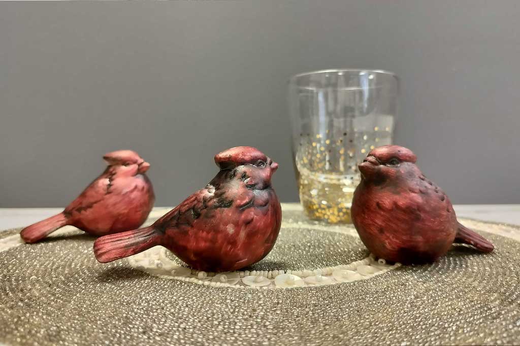 Set of three red cardinal bird figurines on a table with beaded placement