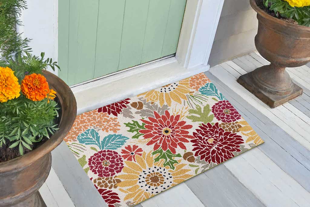 Floral patterned doormat on a wooden floor with potted plants.