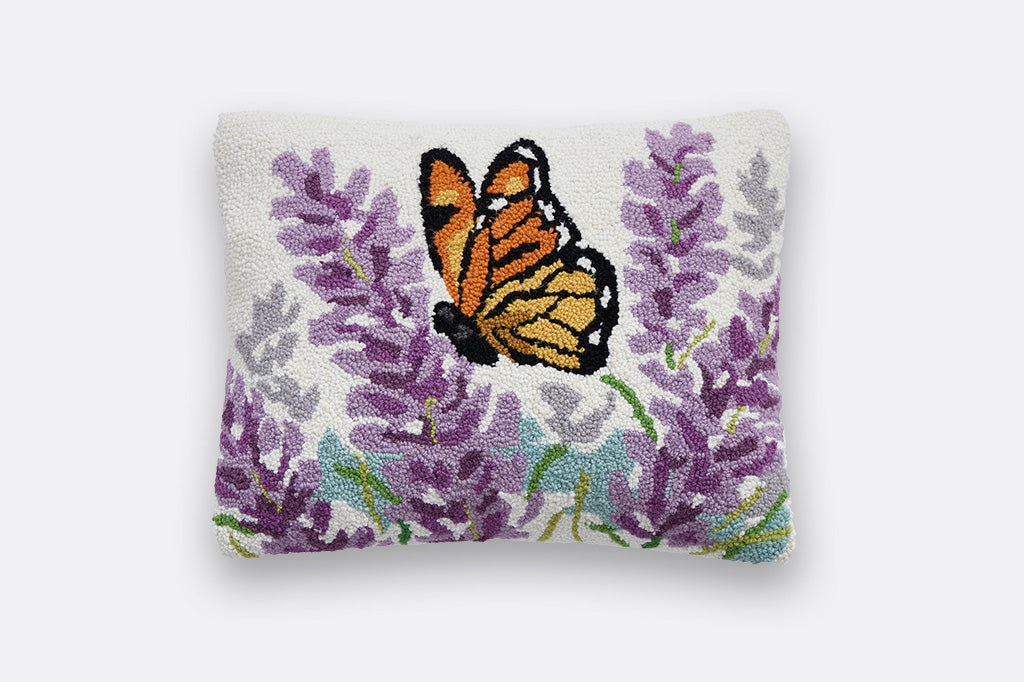  lumbar pillow displays a monarch butterfly flitting about in a field of lavender. Hooked in wool with a polyester velvet backing 