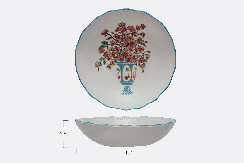 Stoneware bowl with scalloped edges painted in blue with floral arrangement in cheery vase  