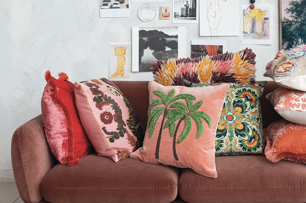 bunch of embroidered pillows on pink couch 