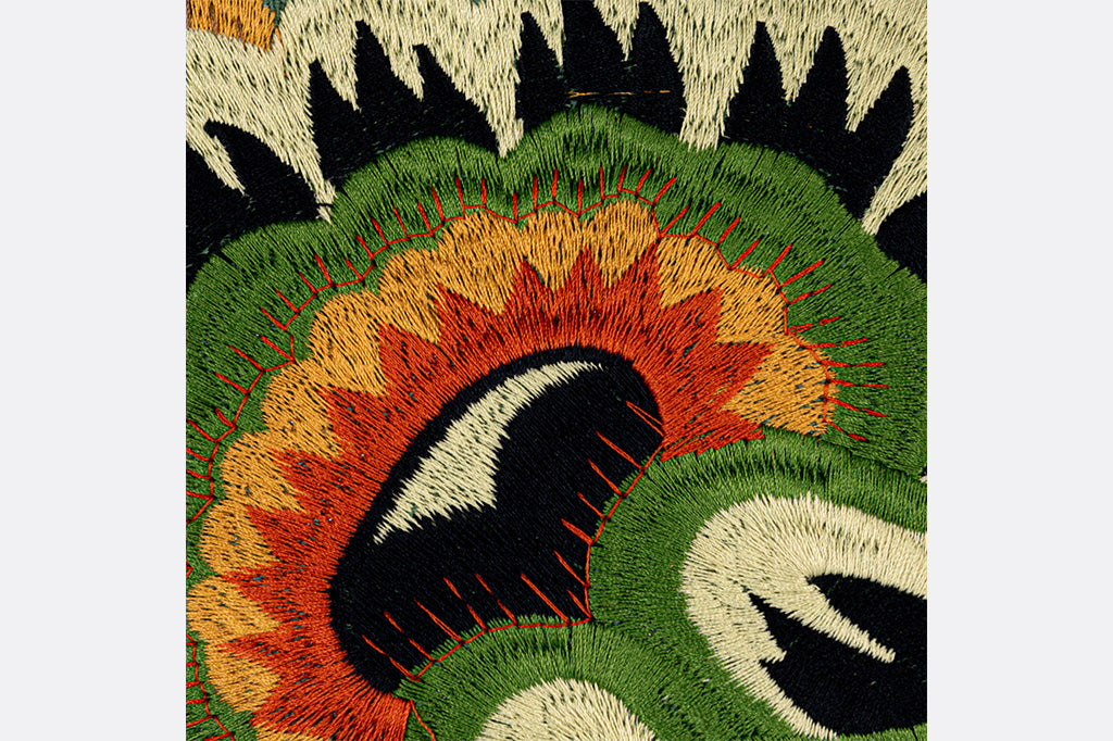 closeup detail of Colorful, kaleidescopic embroidered 18" Square throw pillow in green, yellow, red, and black