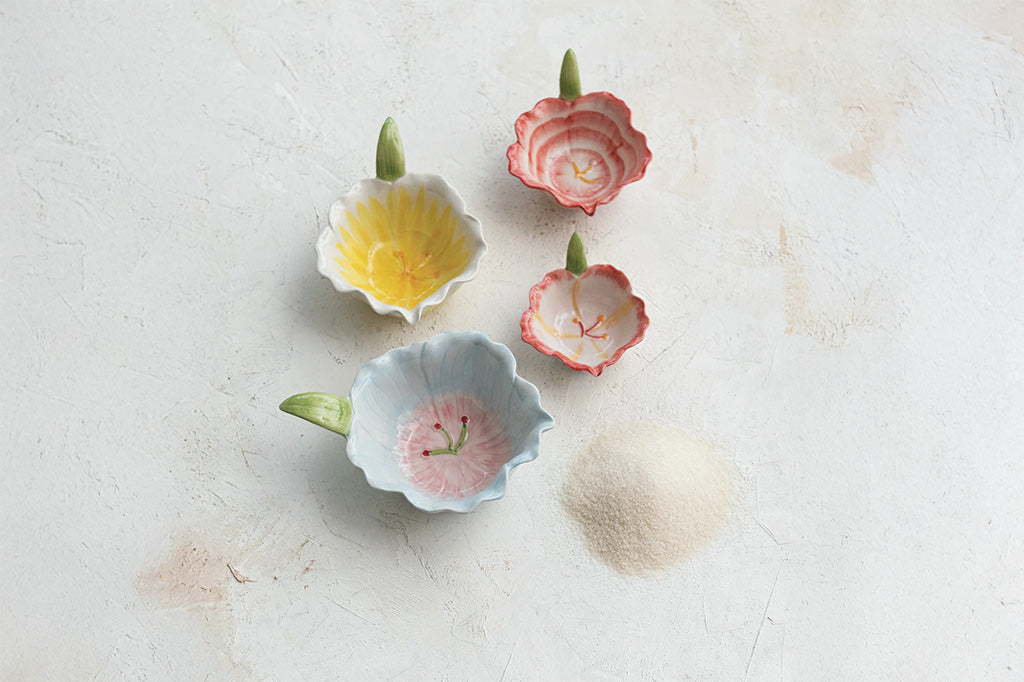 Four small ceramic bowls with floral designs on a cooking surface near spilled flour