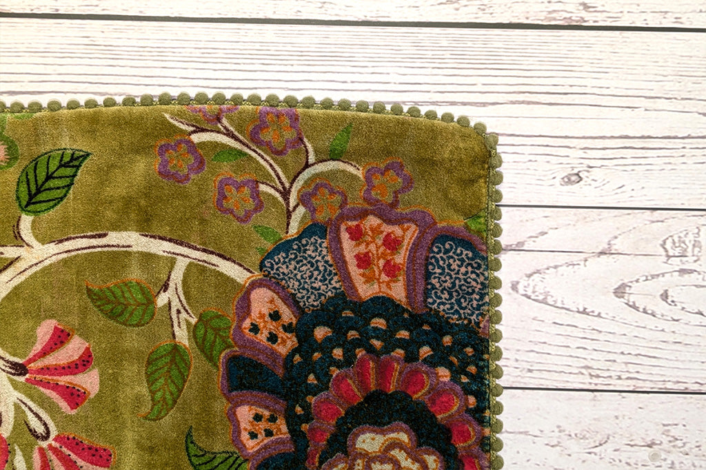 A close up of the edge of a pillow with little pom poms.