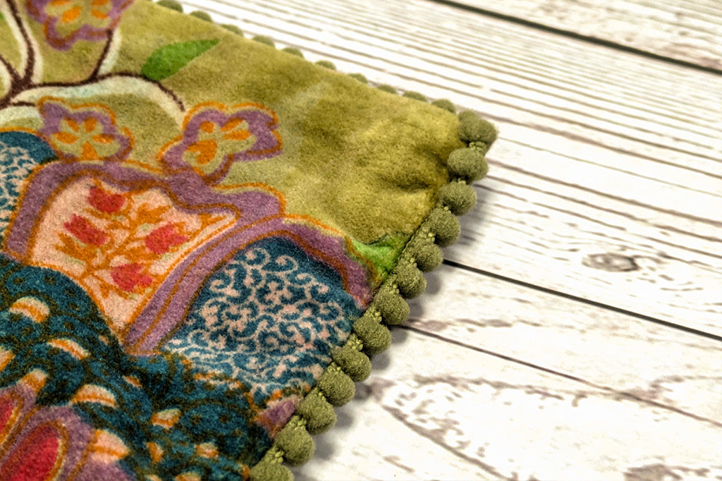 A close up of the edge of a pillow with little pom poms.