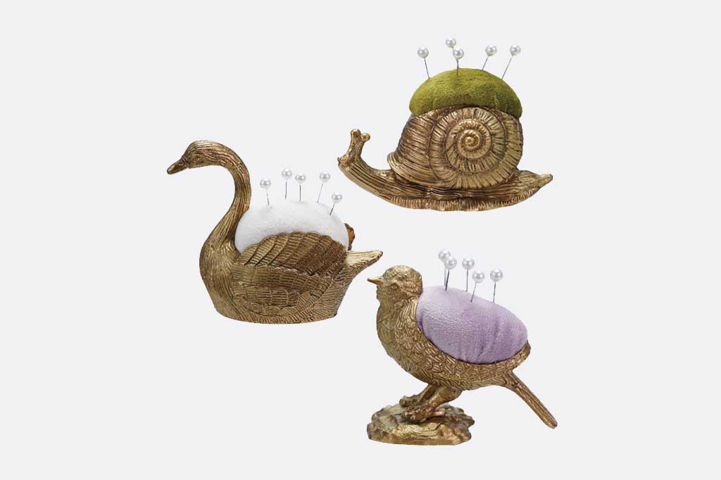 Three decorative pin holders shaped like a swan, snail, and bird on a white background