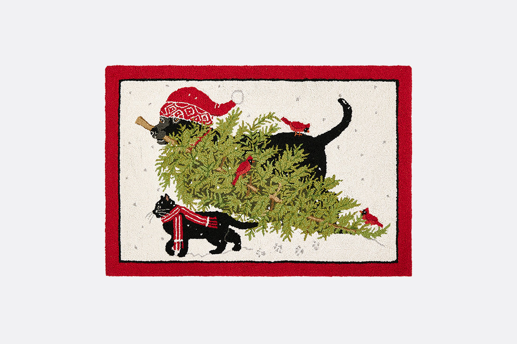 Decorative floormat with black cat and black dog wearing red woolens bringing a Christmas tree design across the snow