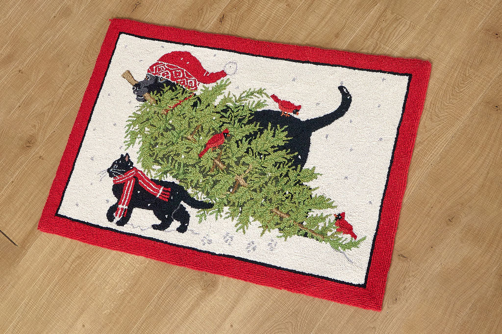 Decorative floormat with black cat and black dog wearing red woolens bringing a Christmas tree design across the snow