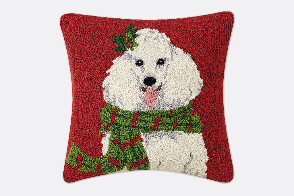 Decorative pillow with a dog wearing a green scarf and holly leaf on a red background