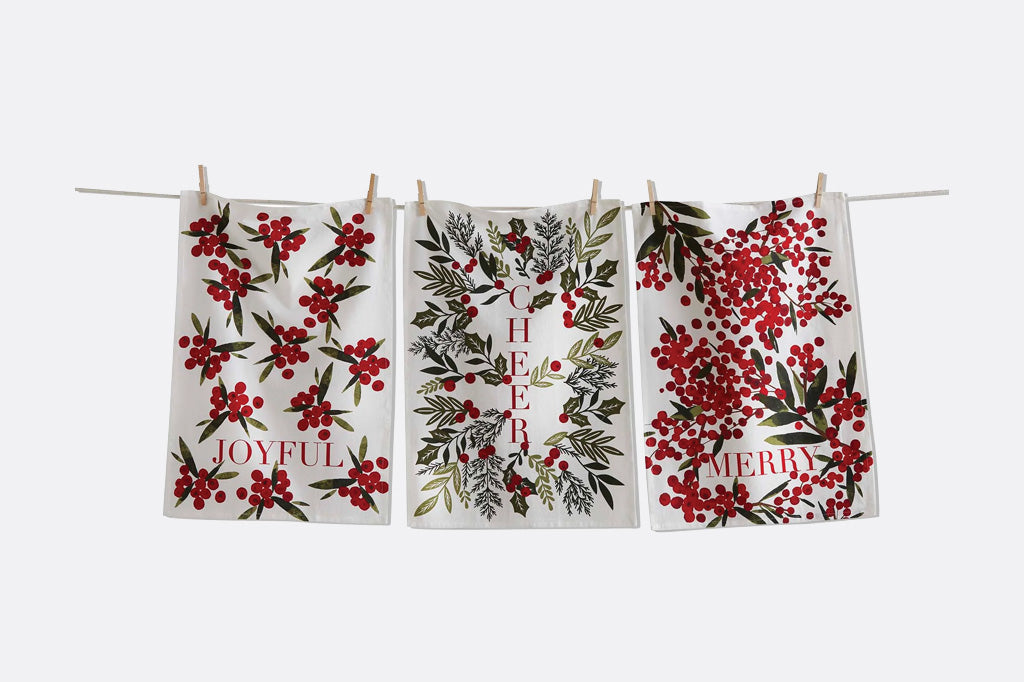 Three holiday botanical printed tea towels on laundry line: they say JOYFUL, CHEER, and MERRY