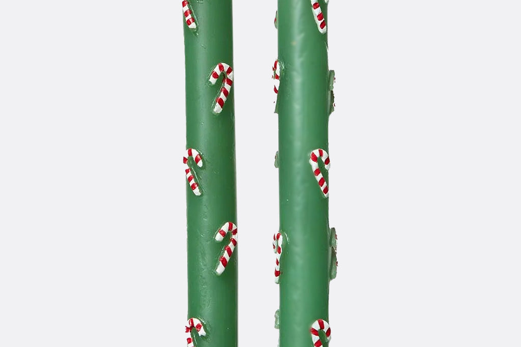 Two green candles with candy cane patterns on a white background