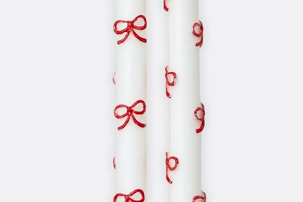 White candles with red bow designs on a white background