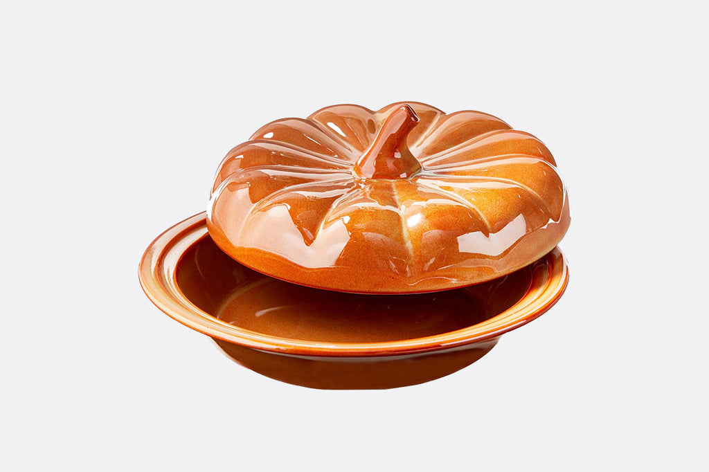 Ceramic pumpkin-shaped dish with lid on a white background