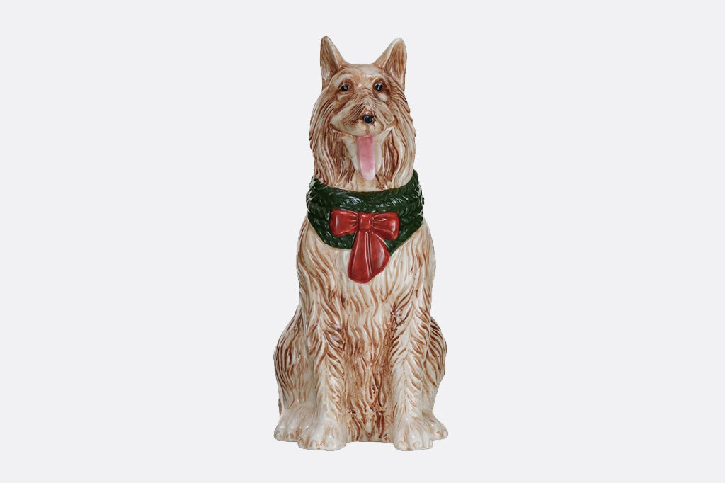 Dog vase wearing a green collar with a red bow on a white background