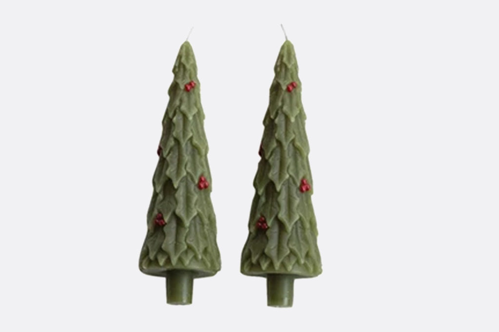 close up view of two holly motif tree-shaped taper candles