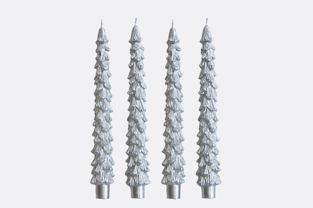 Four silver tree-shaped candles on a light gray background