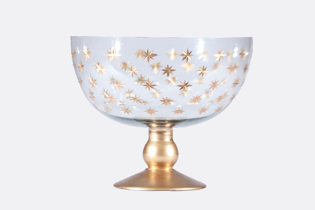 Decorative glass footed serving bowl with gold star pattern on a white background