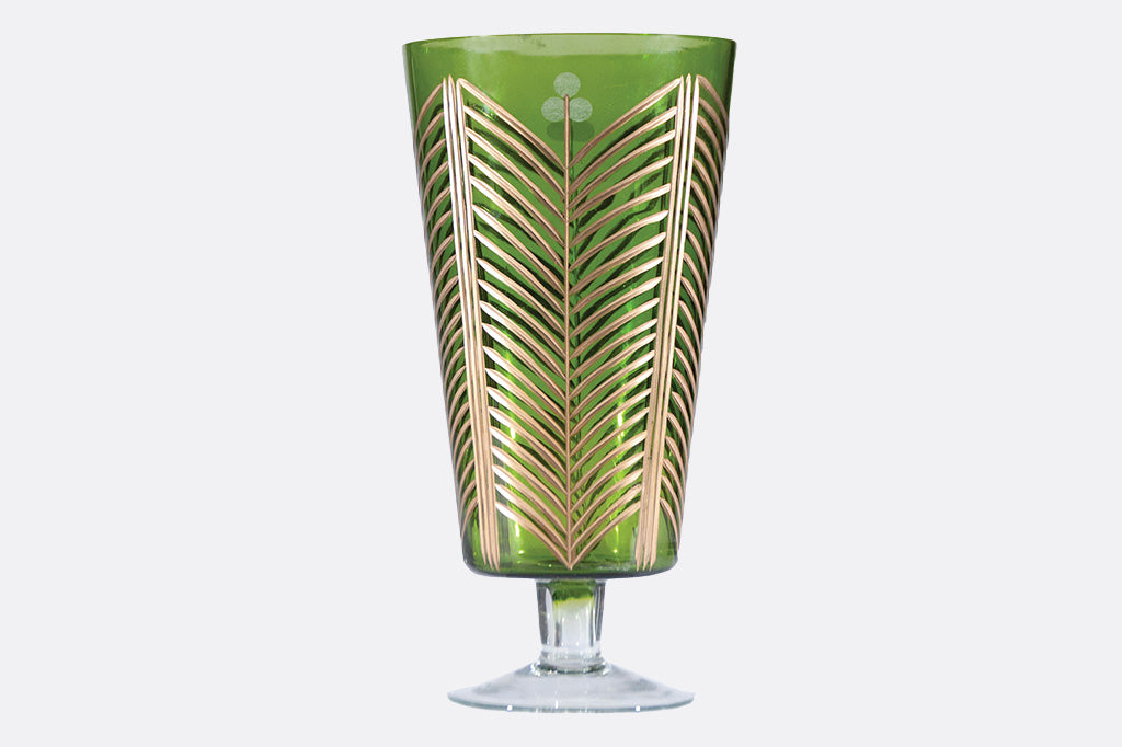 Green glass with gold leaf pattern on a white background