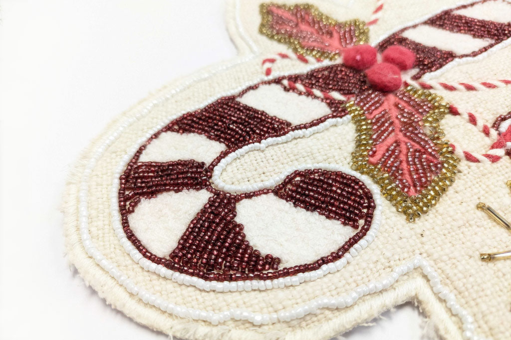 Close-up of a beaded table runner with Christmas ornament with candy cane design on a white background