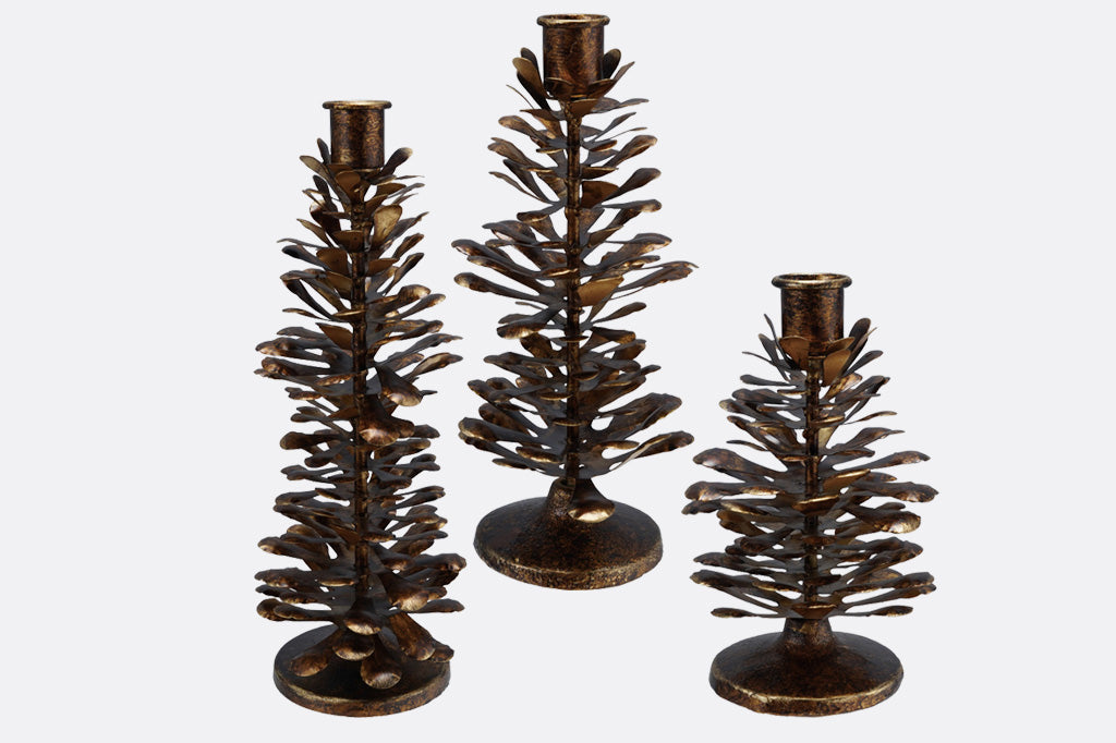 Three metallic tree-shaped candle holders on a white background