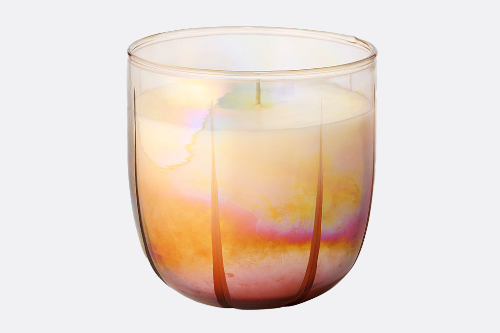 Iridescent glass candle with a white candle inside on a white background