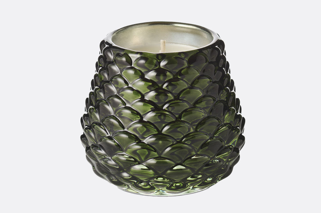 Pinecone green glass textured candle holder with a candle inside on a white background