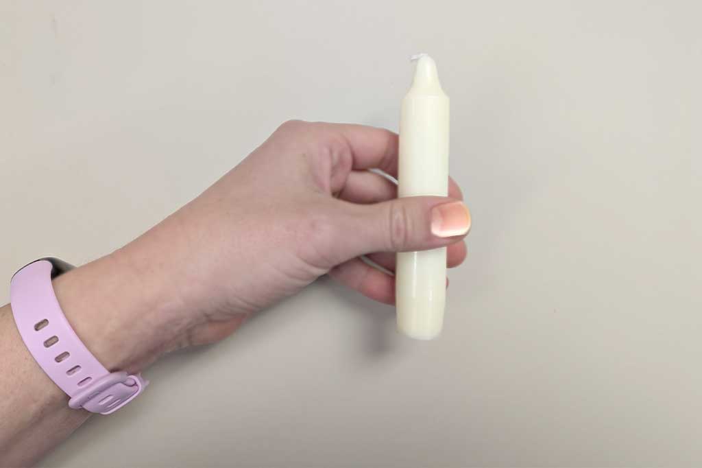 single hand holding the 5"H short taper candle